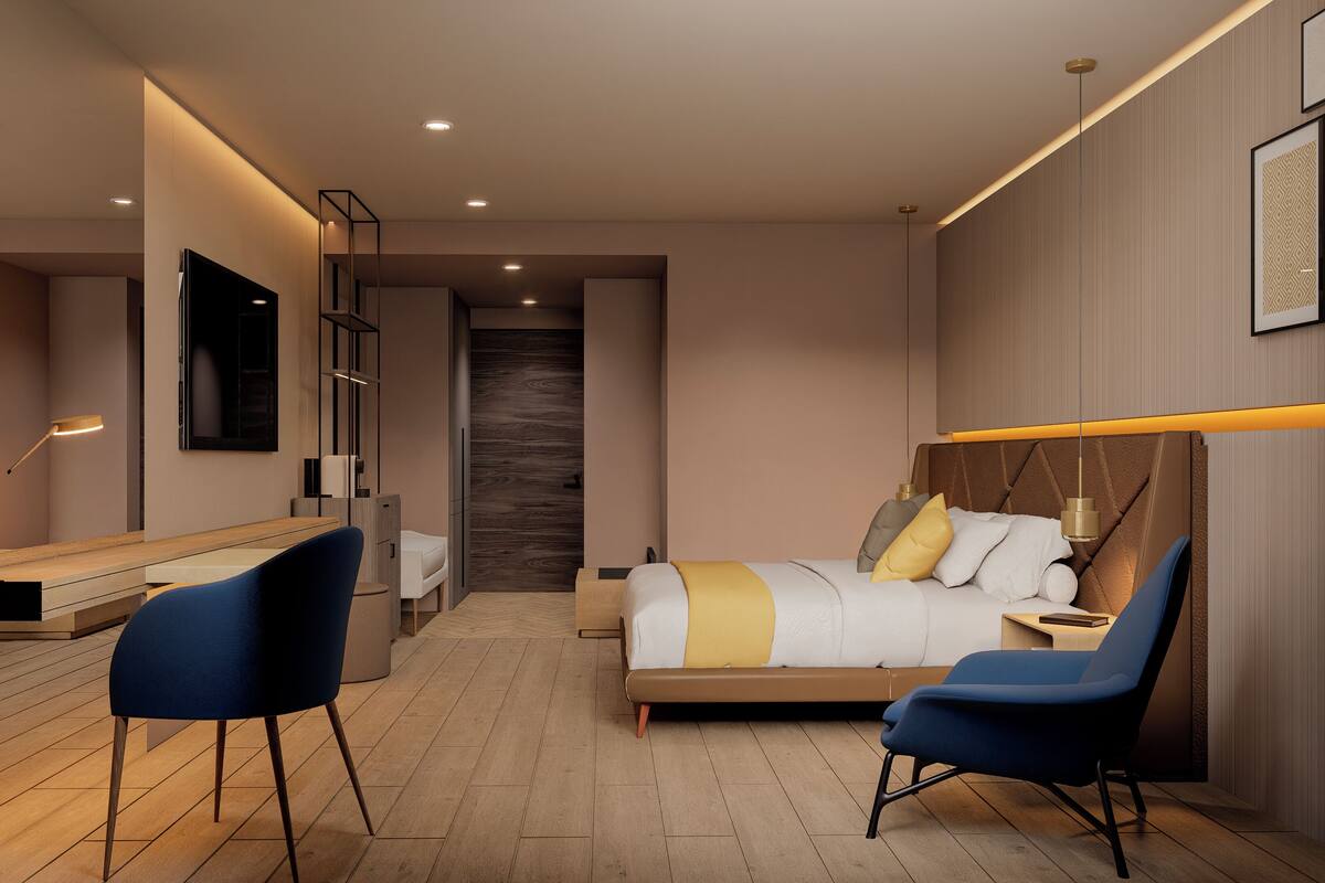 Een moderne slaapkamer met een bed, twee stoelen, een bureau en een grote spiegel.