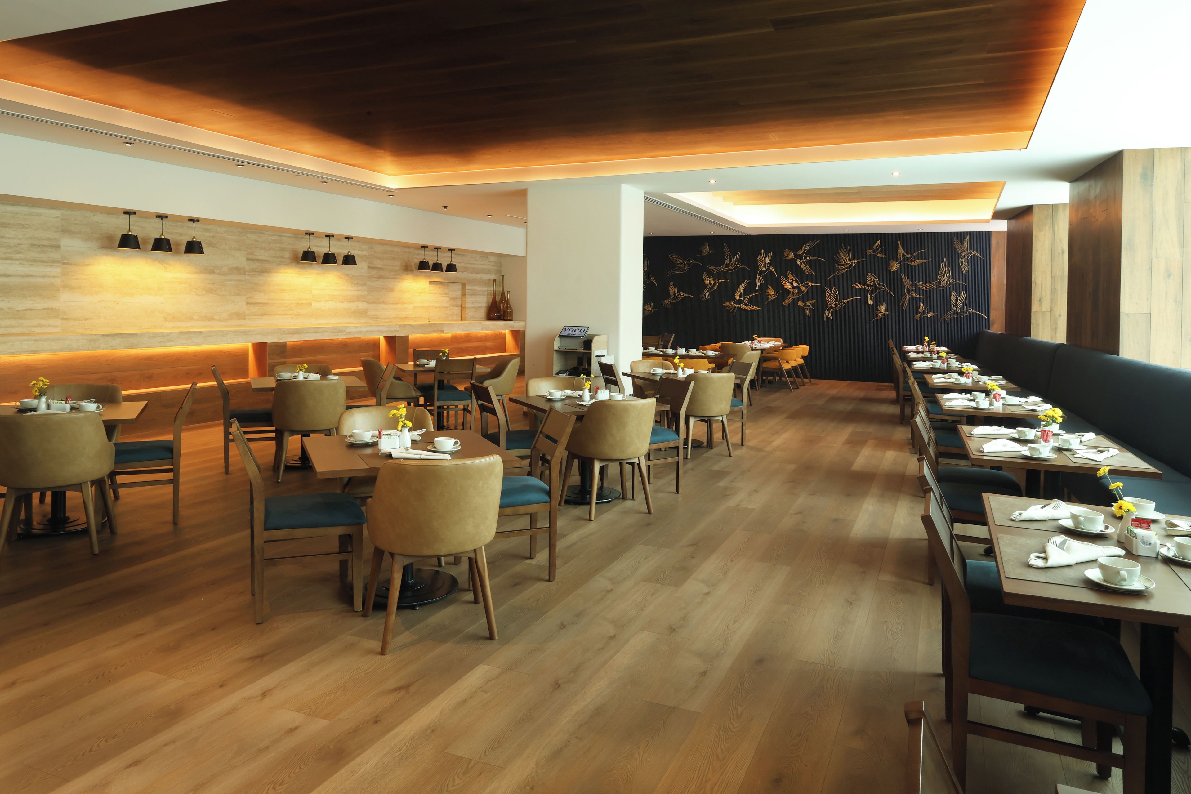 A restaurant with wooden flooring, multiple dining tables, and chairs.