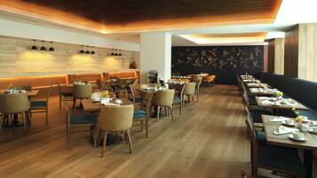 A restaurant with wooden flooring, multiple dining tables, and chairs.