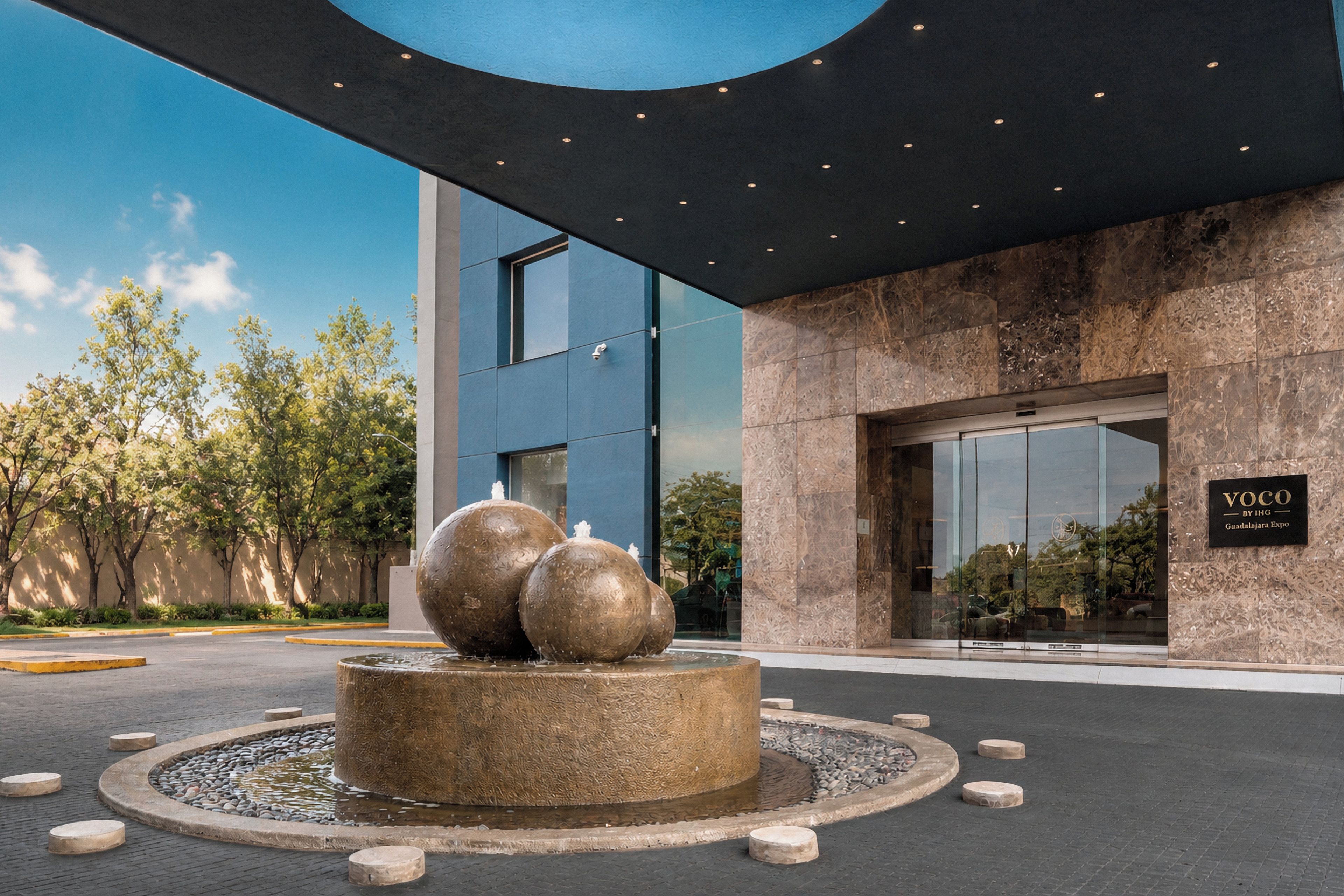 A modern building entrance with a water feature and a sign indicating the name 'VOCO'.