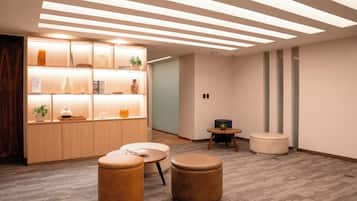A modern interior with a wooden cabinet, round ottomans, and a small round table.