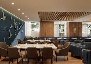 A modern dining area with a long table, multiple chairs, and a blue accent wall with a bird mural.