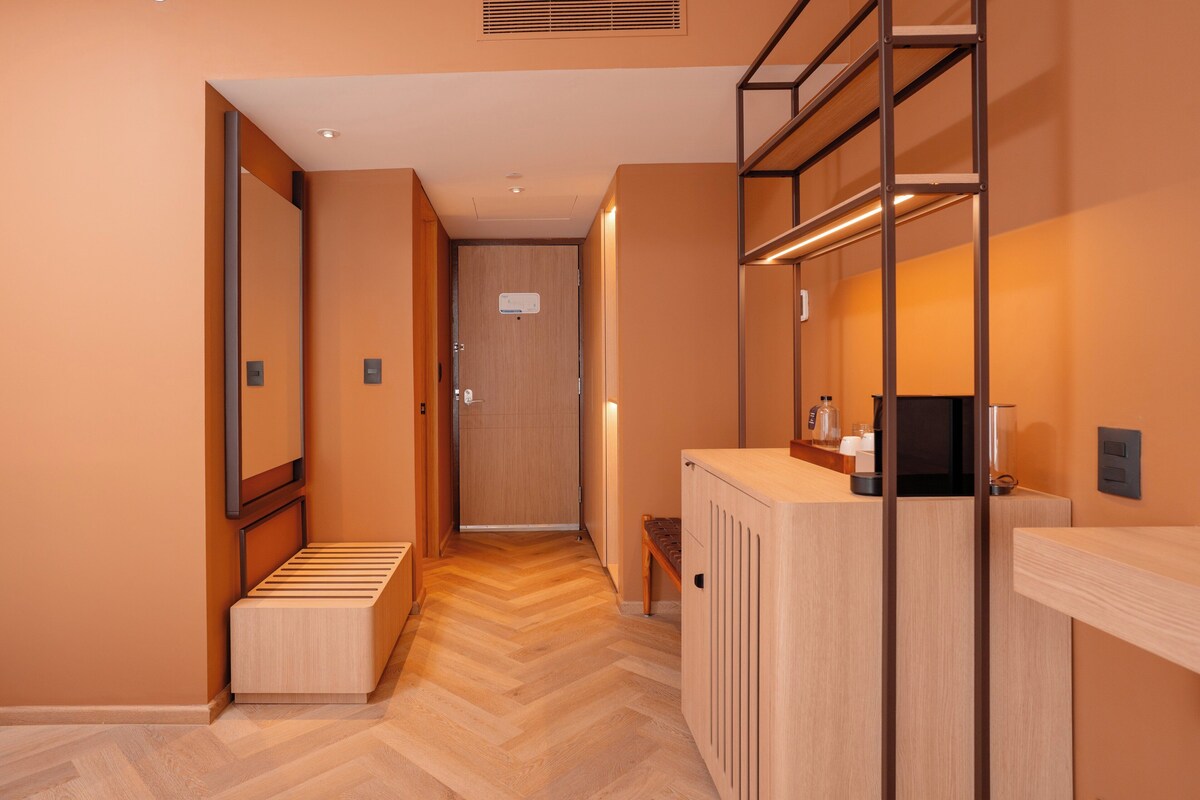 Een hotelgang met een houten vloer, een receptiebalie en een deur.