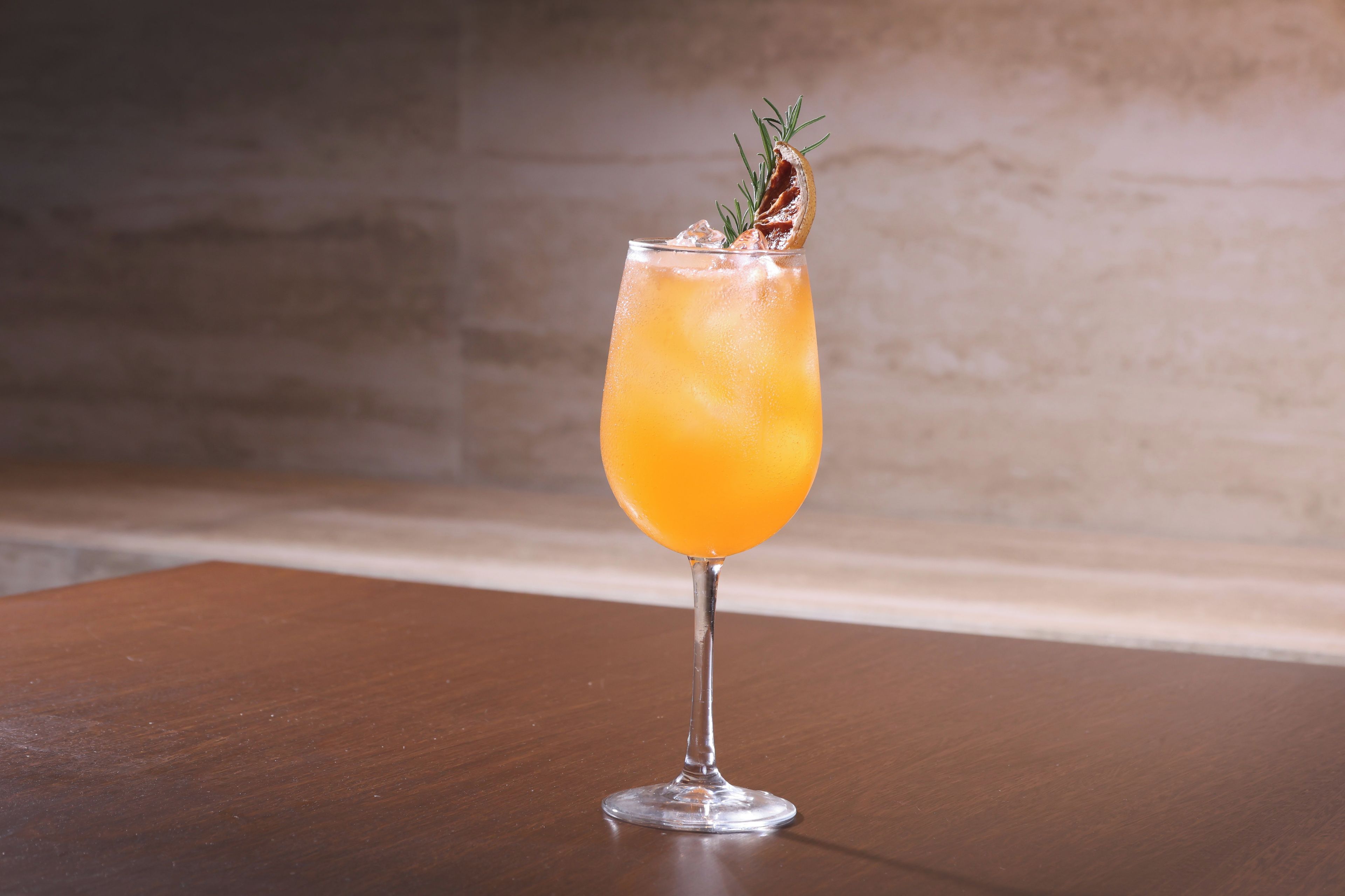 A clear glass with a beverage on a wooden surface.