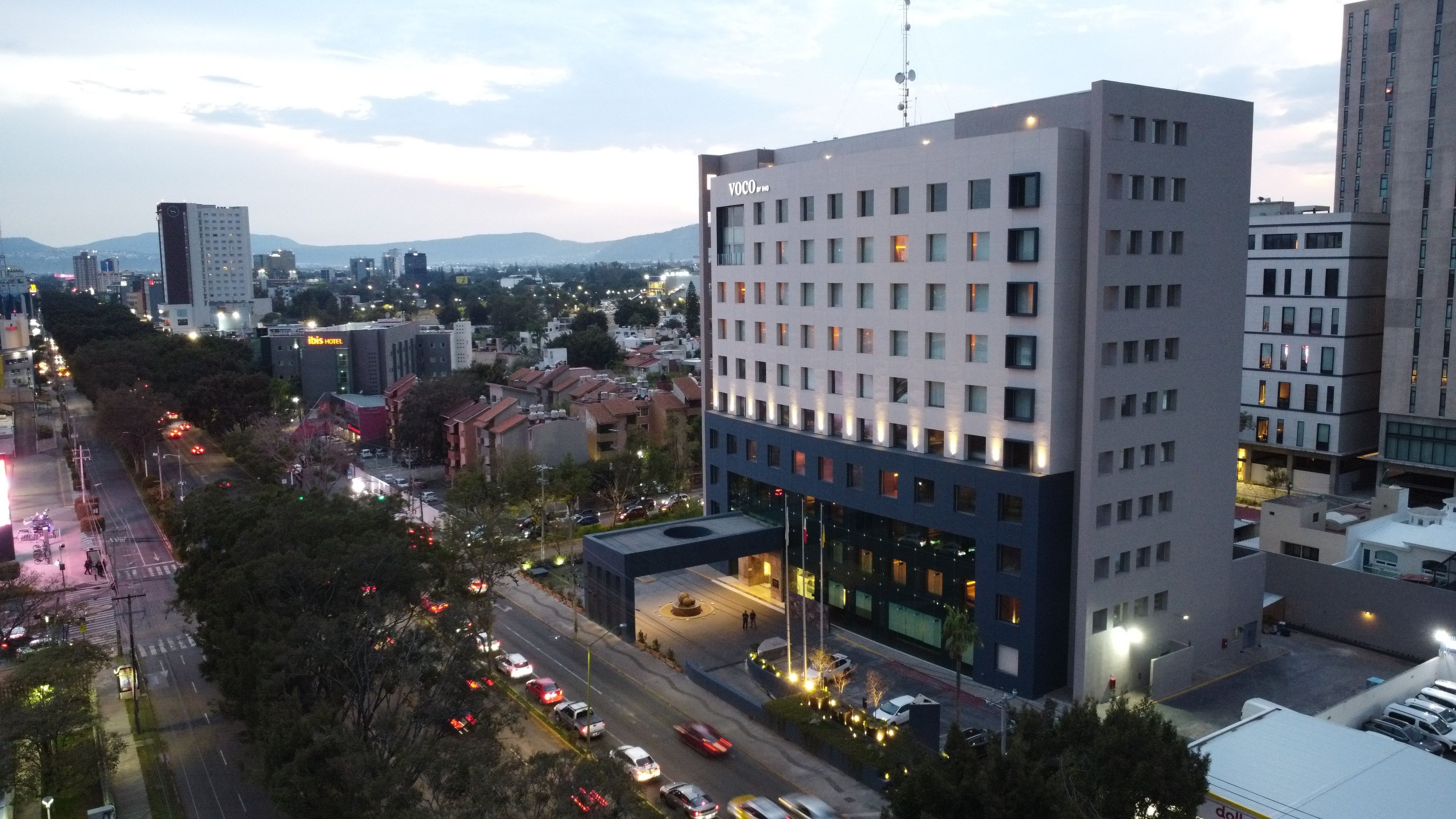 Un hotel de varios pisos con un diseño moderno, que cuenta con una entrada destacada y vistas de la ciudad circundante.