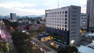 A multi-story hotel with a modern design, featuring a prominent entrance and a view of the surrounding cityscape.