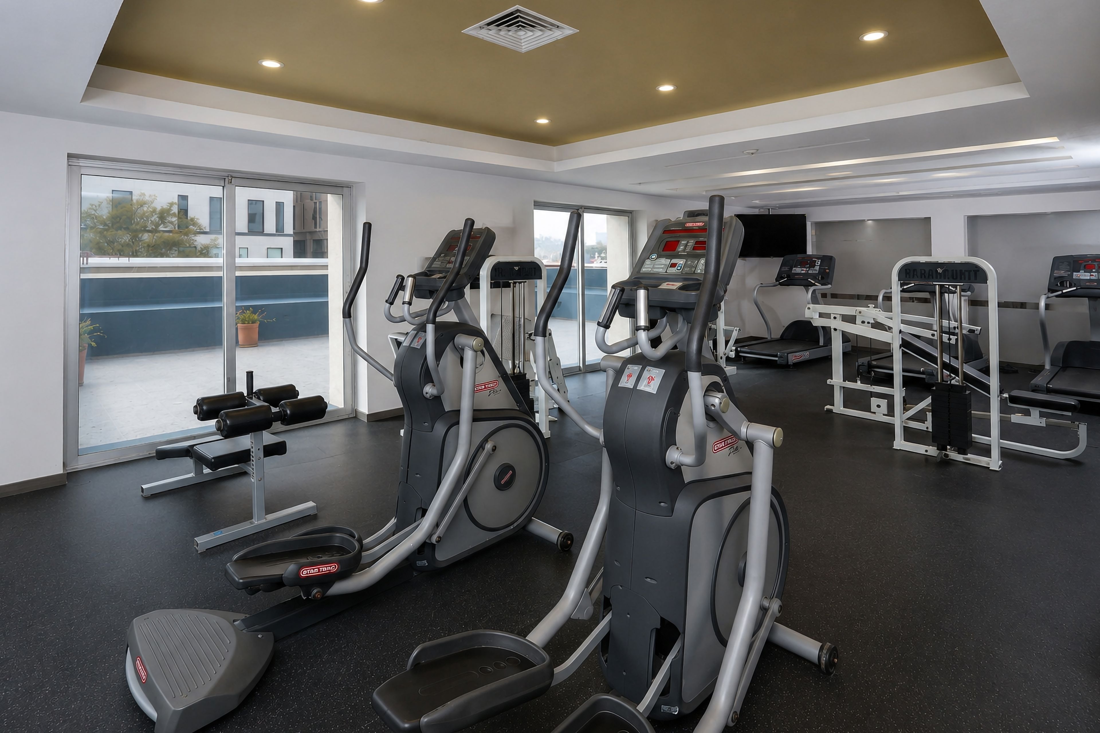 A gym with cardio equipment, weight machines, and a bench press area.