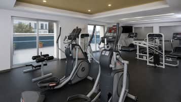 A gym with cardio equipment, weight machines, and a bench press area.