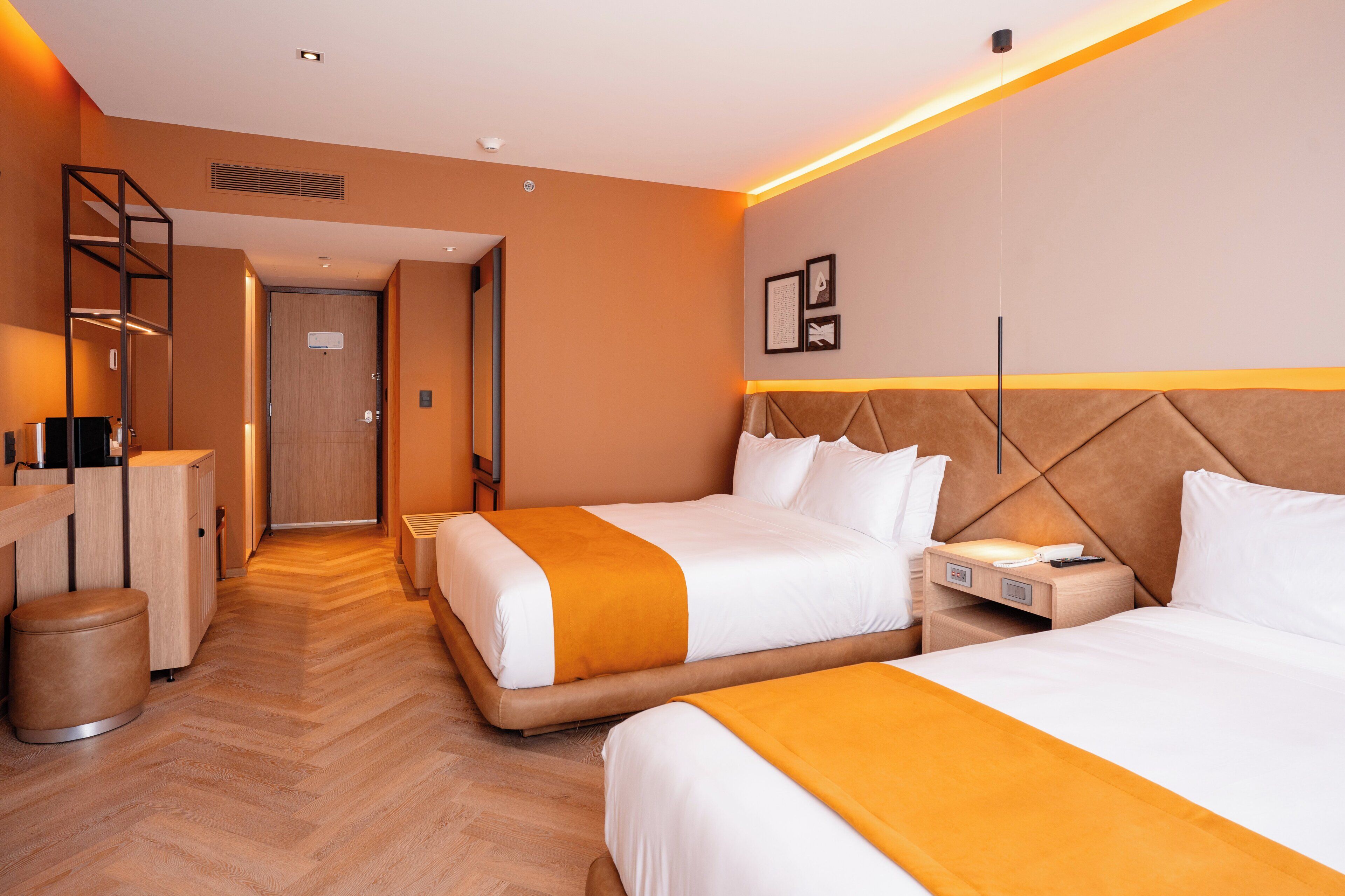 A hotel room with two beds, a desk, a chair, and a wardrobe.