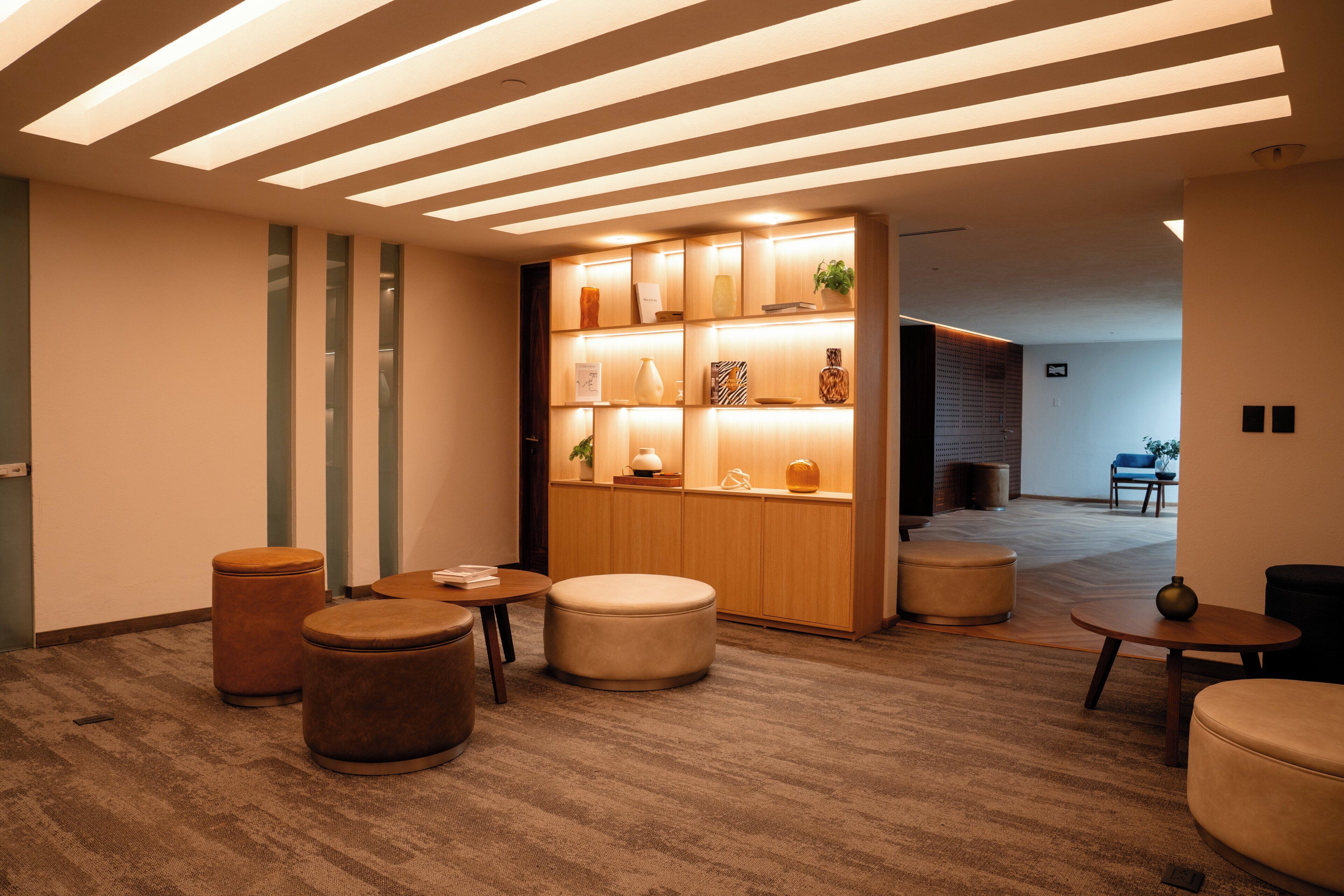 A modern interior with a wooden reception desk, multiple seating options, and a patterned carpet.