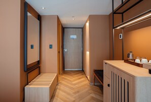Un pasillo de hotel con un banco de madera, una recepción y una puerta con un letrero.