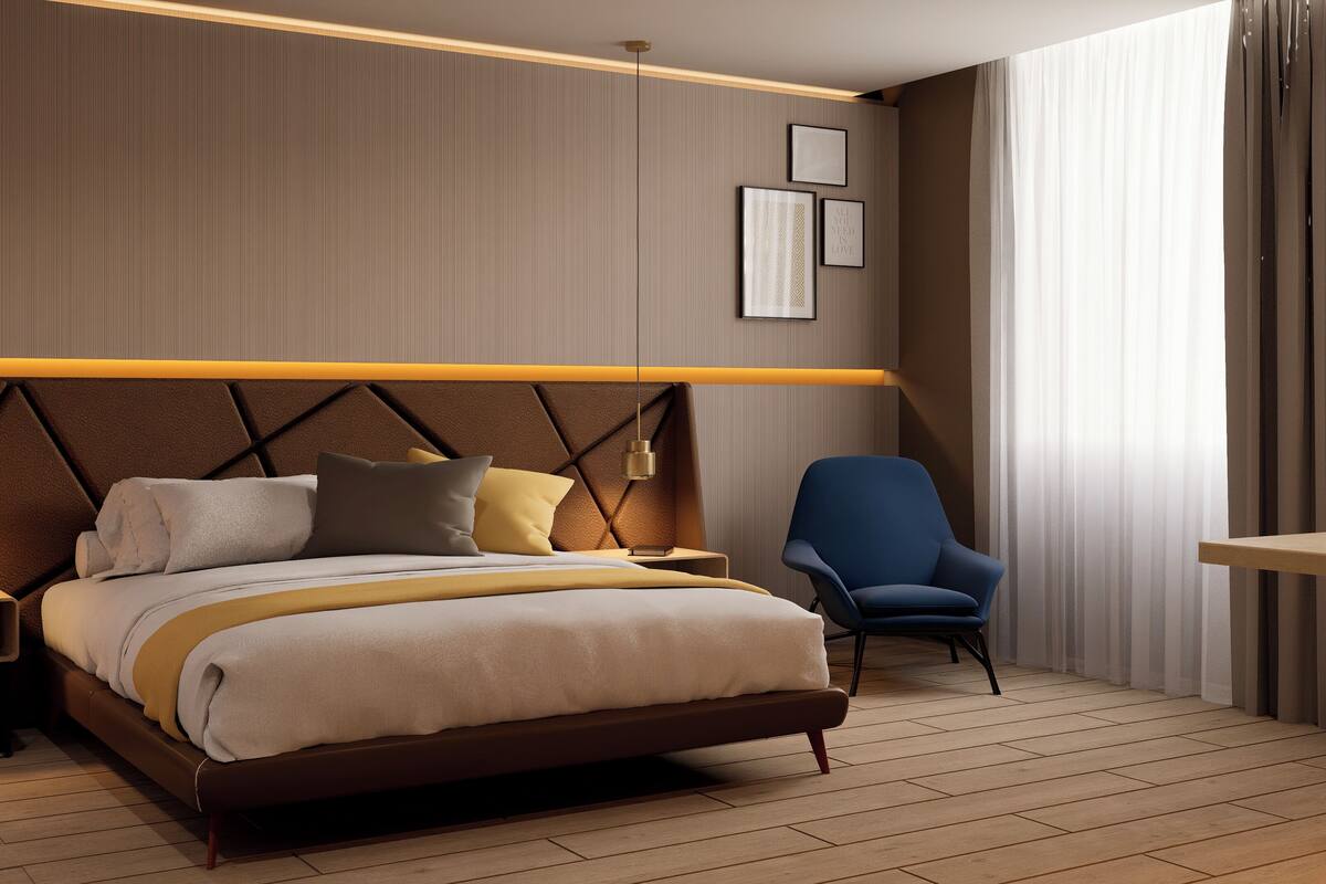 Een moderne hotelkamer met een groot bed, nachtkastjes, een stoel en een wandlamp.