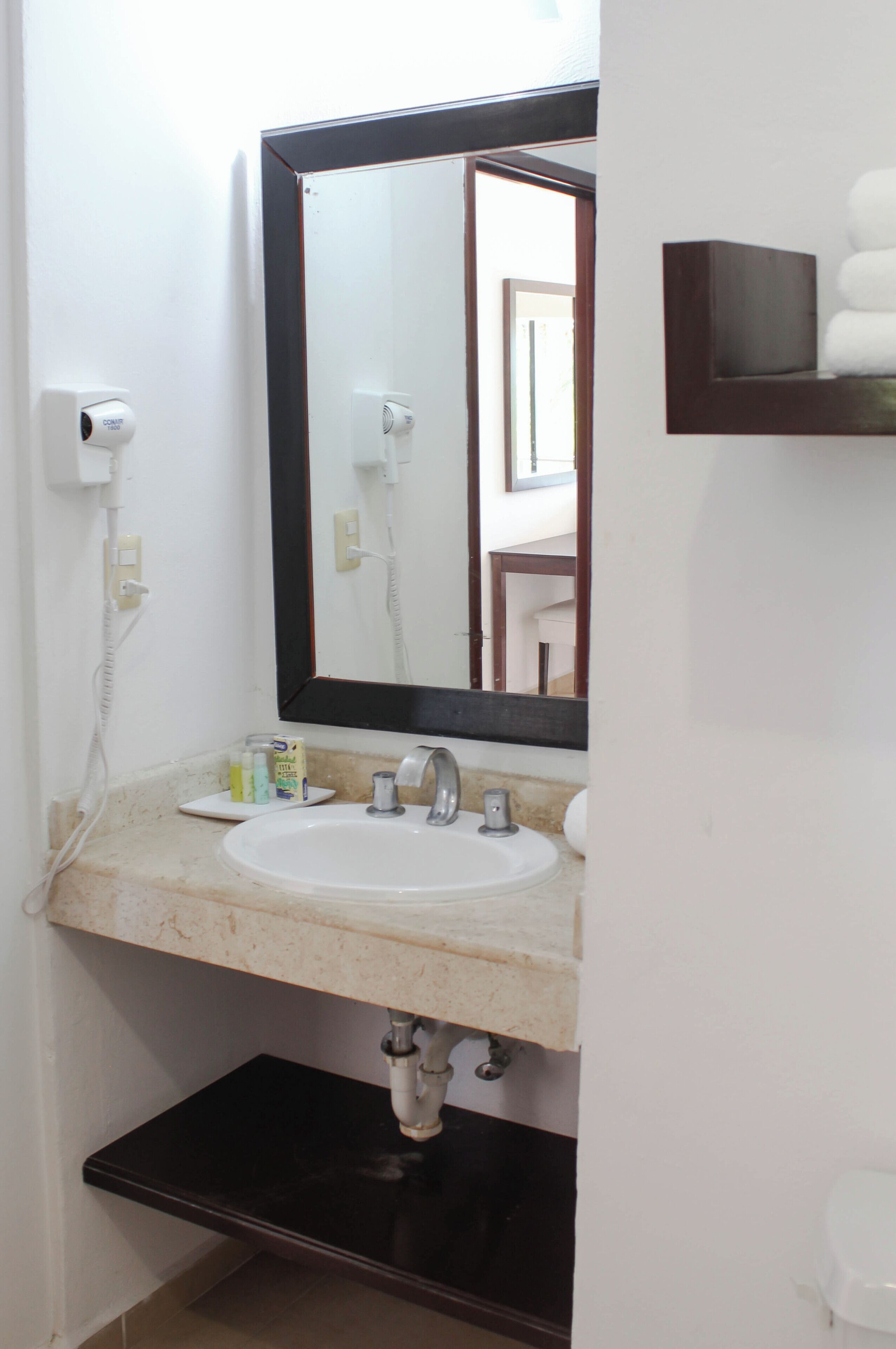 A bathroom with a white sink, a large mirror, a towel rack, and a toilet.