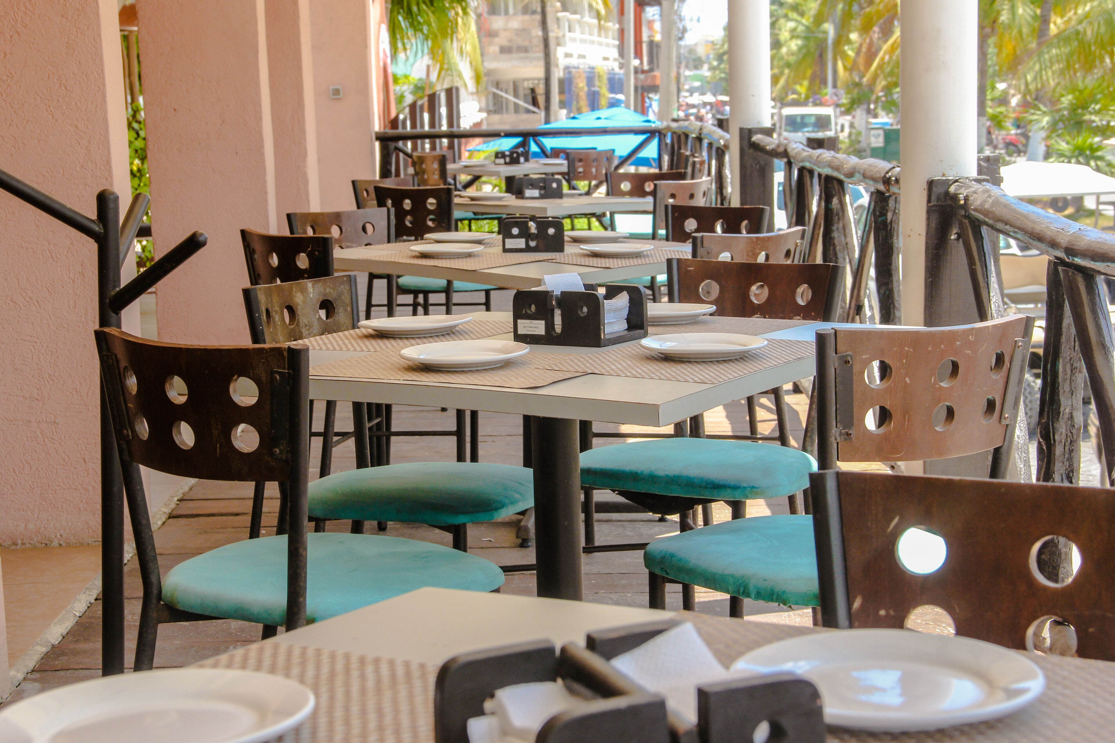 An outdoor dining area with tables and chairs, a railing, and a view of the street.