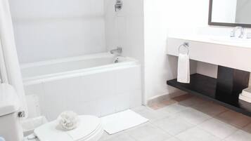 Un baño moderno con bañera, inodoro, lavamanos y espejo.