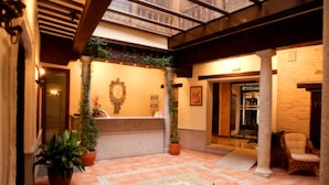 A hotel lobby with a reception desk, potted plants, and a tiled floor. - Hotel Eurico (Toledo)