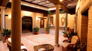 A spacious courtyard with a tiled floor, wicker furniture, and potted plants. - Hotel Eurico (Toledo)