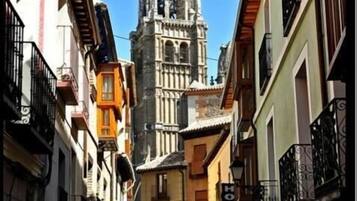 A narrow street with a historic church tower in the background.