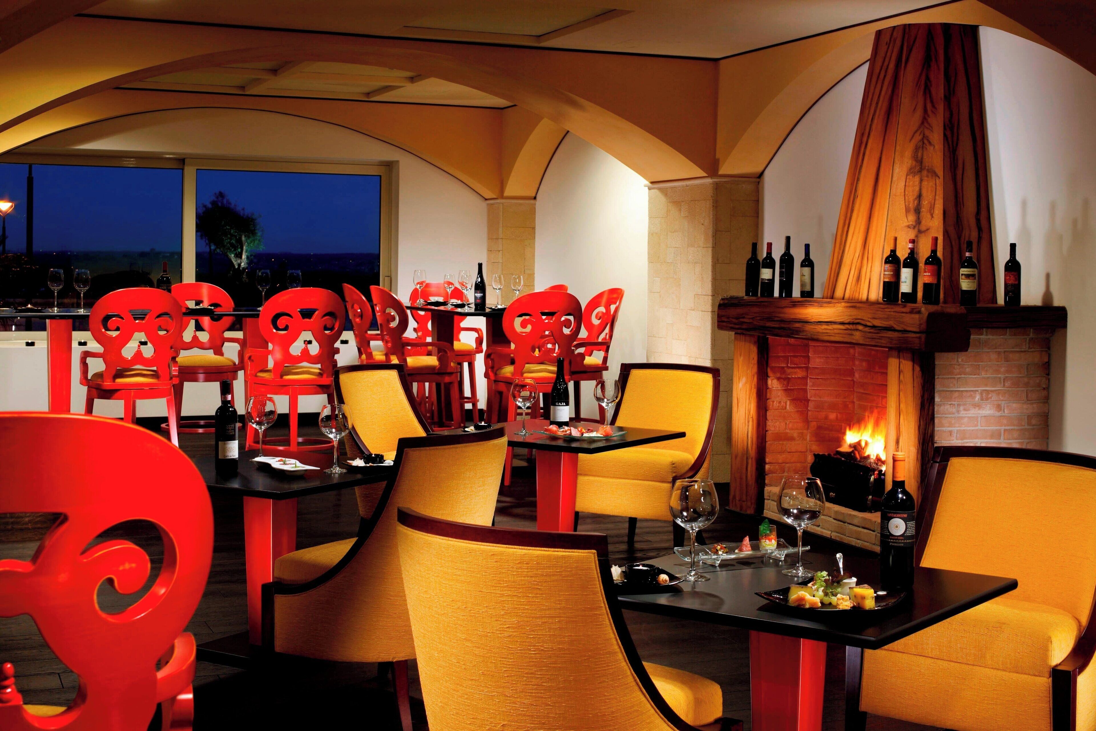Ein Restaurant mit roten Stühlen, gelben Kissen und einem Kamin aus Ziegelsteinen.