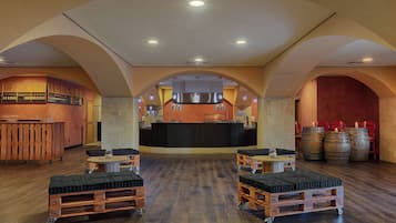 A spacious bar area with a counter, wooden stools, and a bar cart.