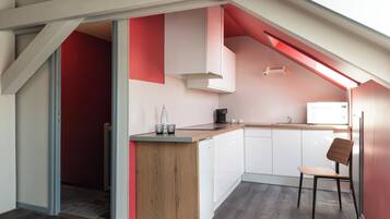 Una cocina moderna con encimera de madera, armarios blancos y una pared de acento roja.