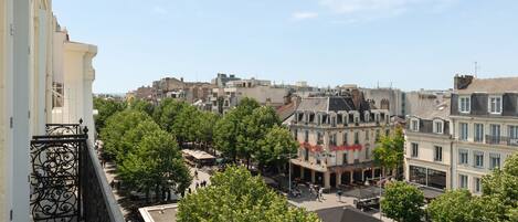 A cityscape with buildings, trees, and outdoor seating areas.