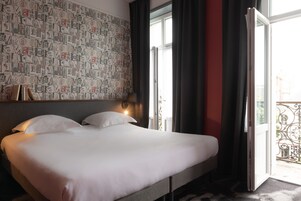 Habitación de hotel con una cama grande, un papel tapiz estampado y vistas al exterior.