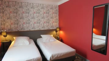 A hotel room with two beds, a red wall, and a patterned wallpaper.
