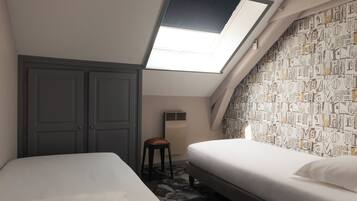 Een ruime, goed verlichte kamer met dakraam, twee bedden, een kledingkast en een radiator.