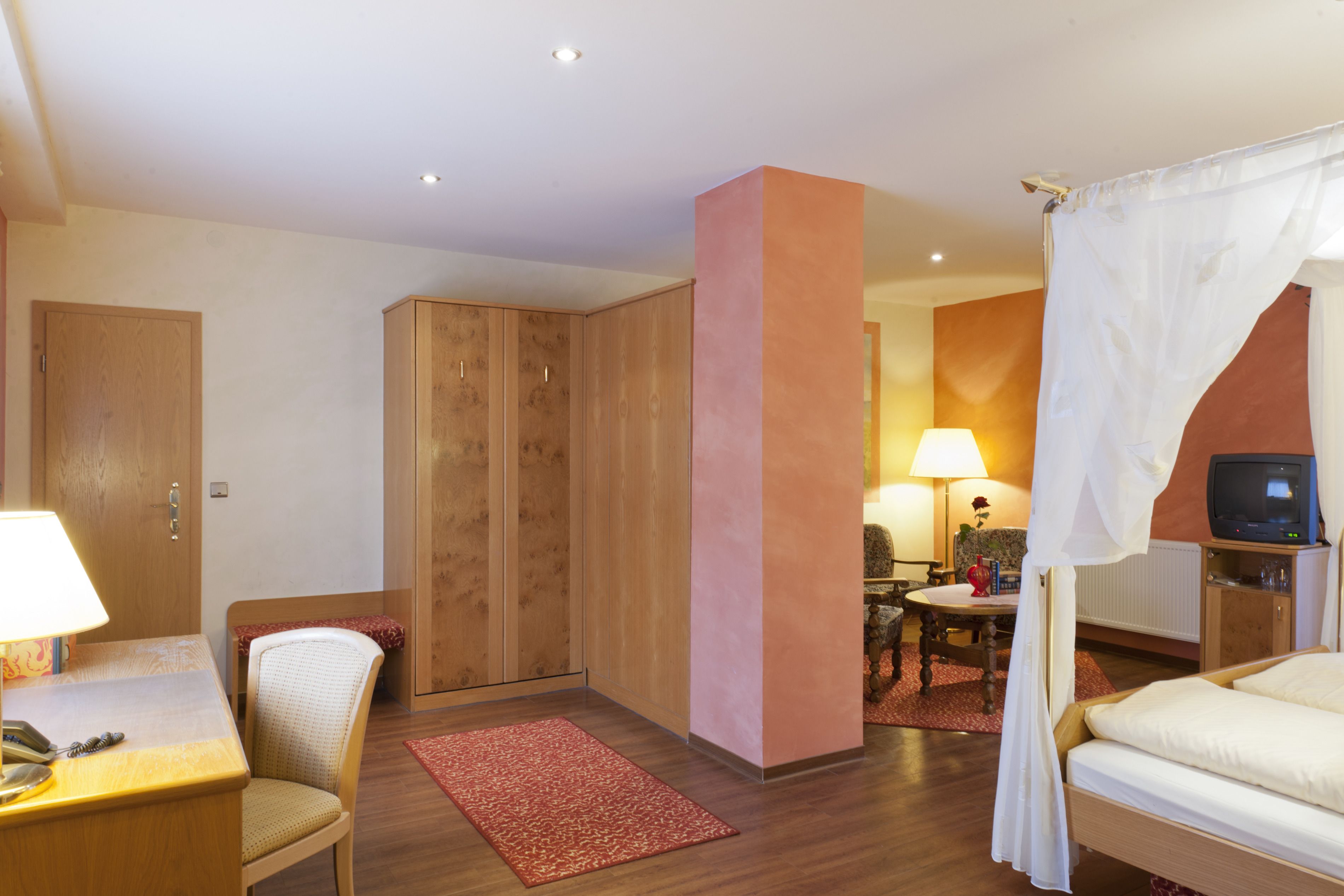 Une chambre d’hôtel comprenant un lit, un bureau avec une lampe, une chaise, une armoire et un téléviseur.