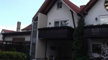 Uma casa de dois andares com telhado de telhas vermelhas, uma varanda e uma garagem.