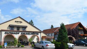 A hotel named "Gutshof Ziegelhütte" with outdoor seating and a parking area.