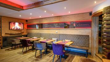 A restaurant with wooden walls, tables, and chairs. There is a menu board with drink options.