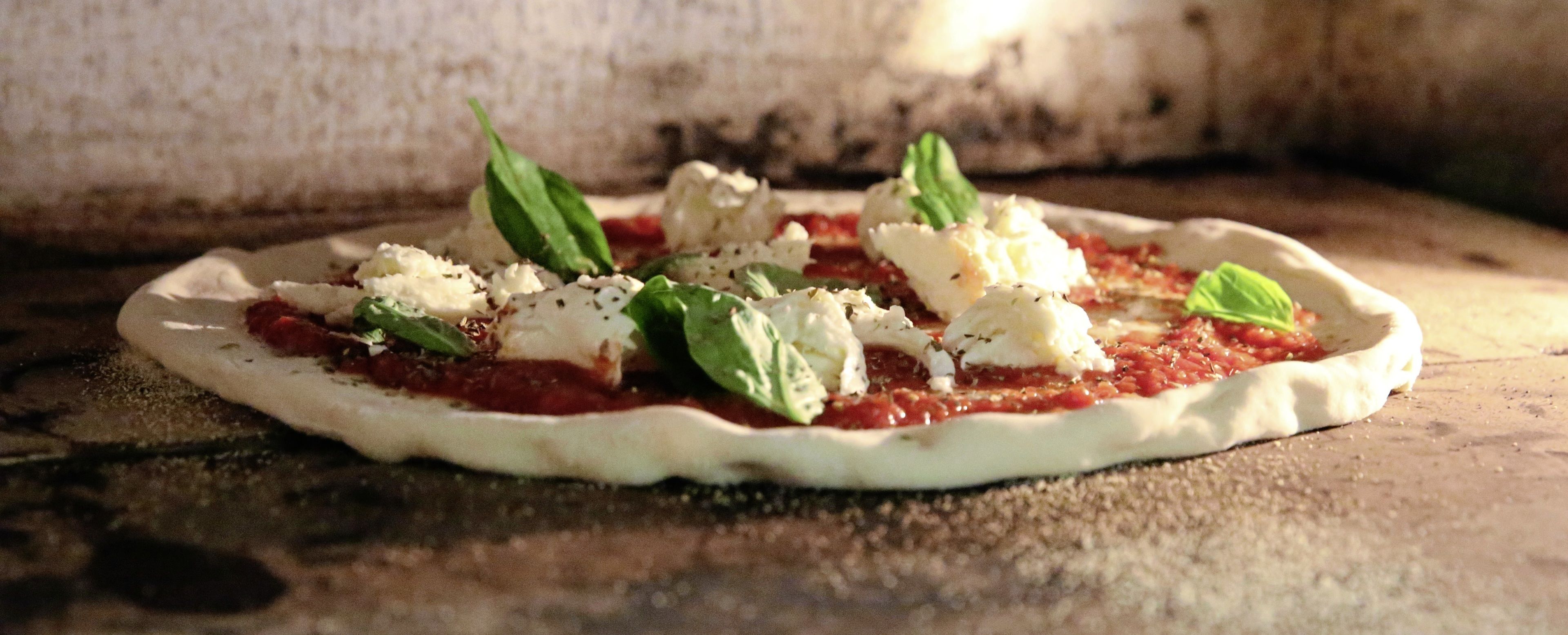 A pizza with cheese and basil on a wooden surface.
