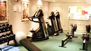 A gym with cardio machines, dumbbells, and a bench. - La Trelade Hotel (St. Martins)