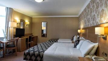 Ein Hotelzimmer mit zwei Betten, einem Schreibtisch, einem Fernseher und einem Telefon.