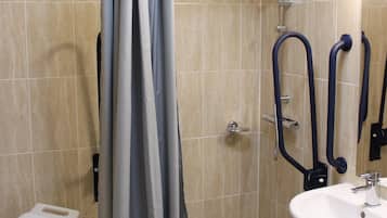 Un baño con ducha, lavabo y un pequeño taburete.