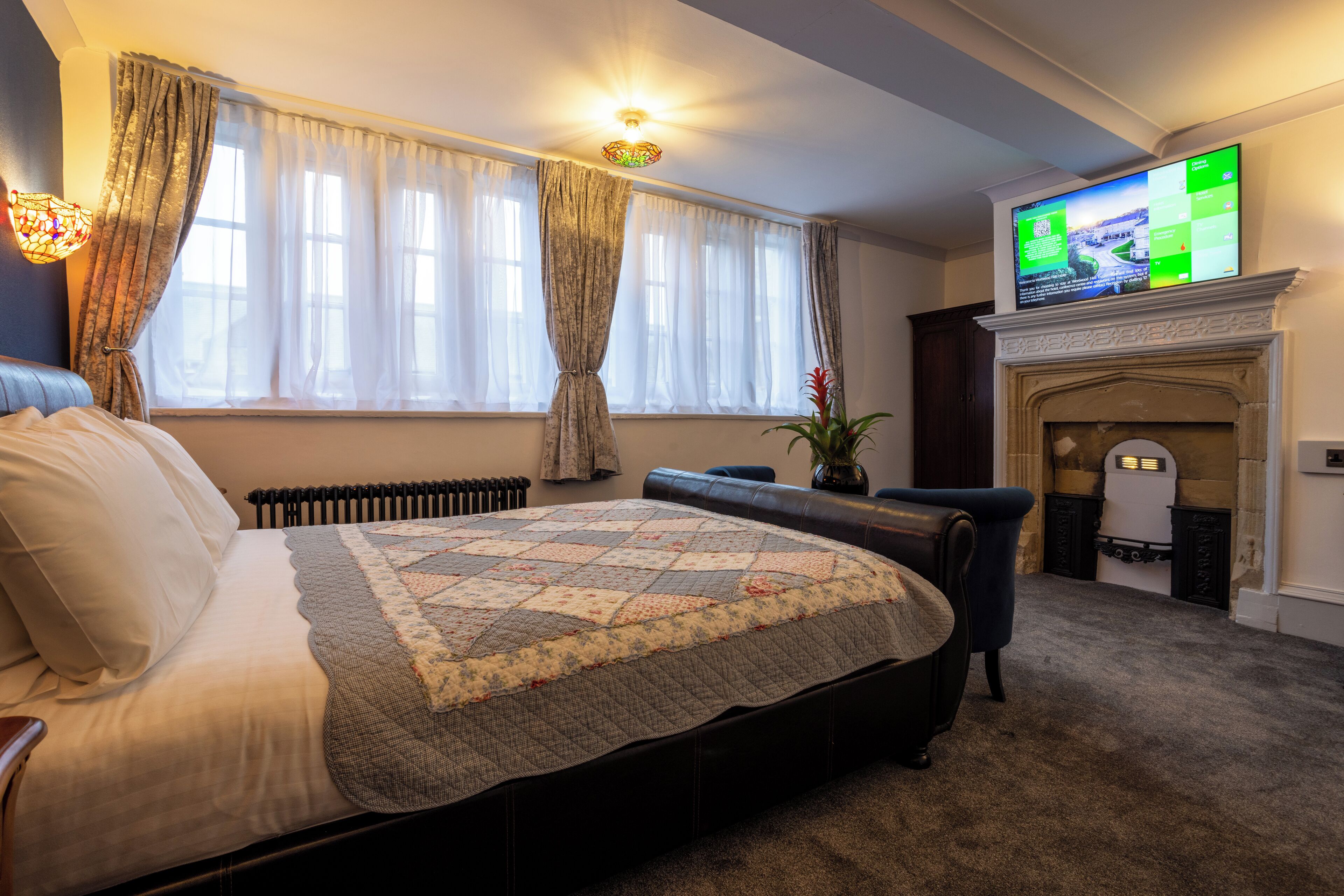 Un dormitorio con una cama grande, una chimenea y un televisor en la pared.