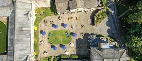 An aerial view of a courtyard with a central lawn, surrounded by buildings with stone facades and multiple windows.
