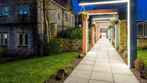 A pathway leading to a building with hanging planters and a stone wall. - Weetwood Hall Conference Centre & Hotel (Leeds)