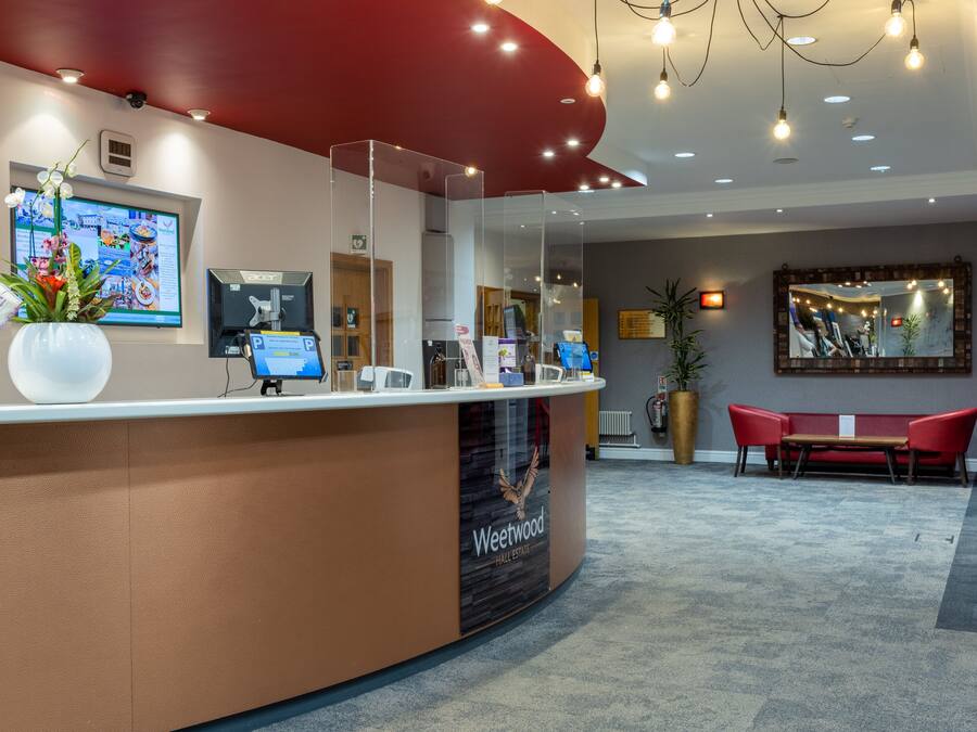 A reception desk with a computer, a plant, and a seating area with a red couch.