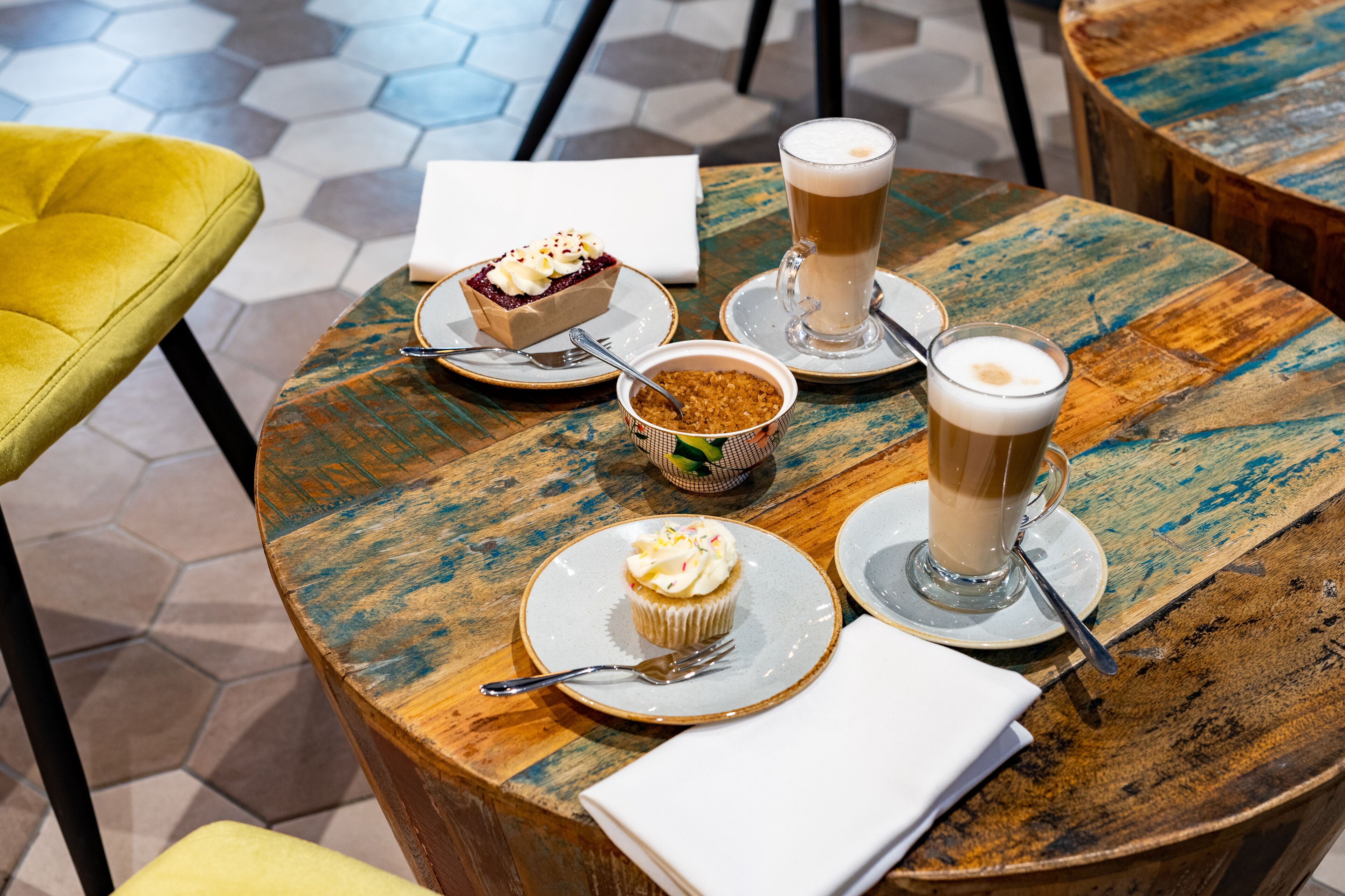 A table with a dessert, a cup of coffee, and a small bowl of nuts.