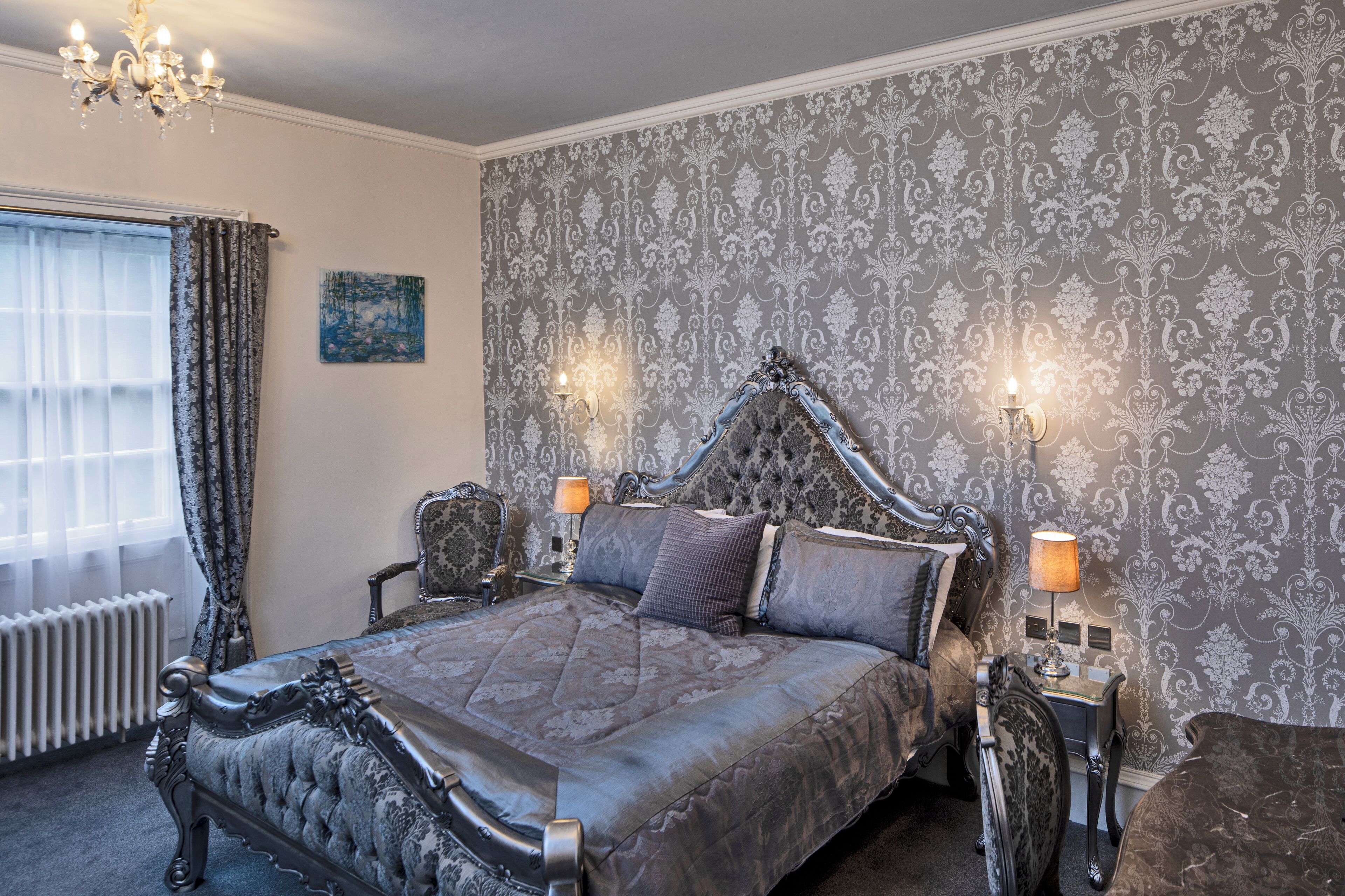 A classic bedroom with a large bed, ornate headboard, and two bedside lamps.