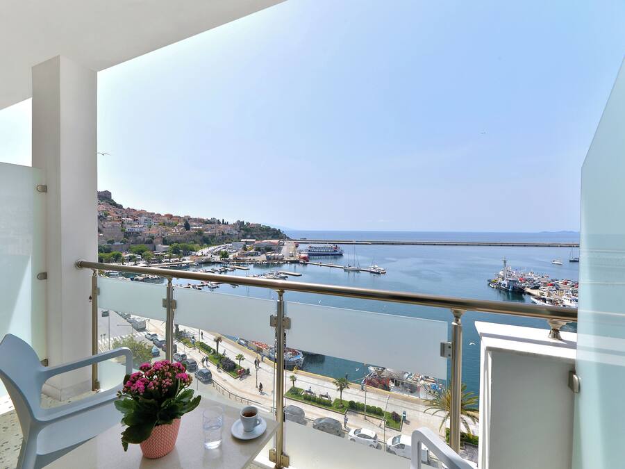 A balcony with a view of a marina and a coastal town.
