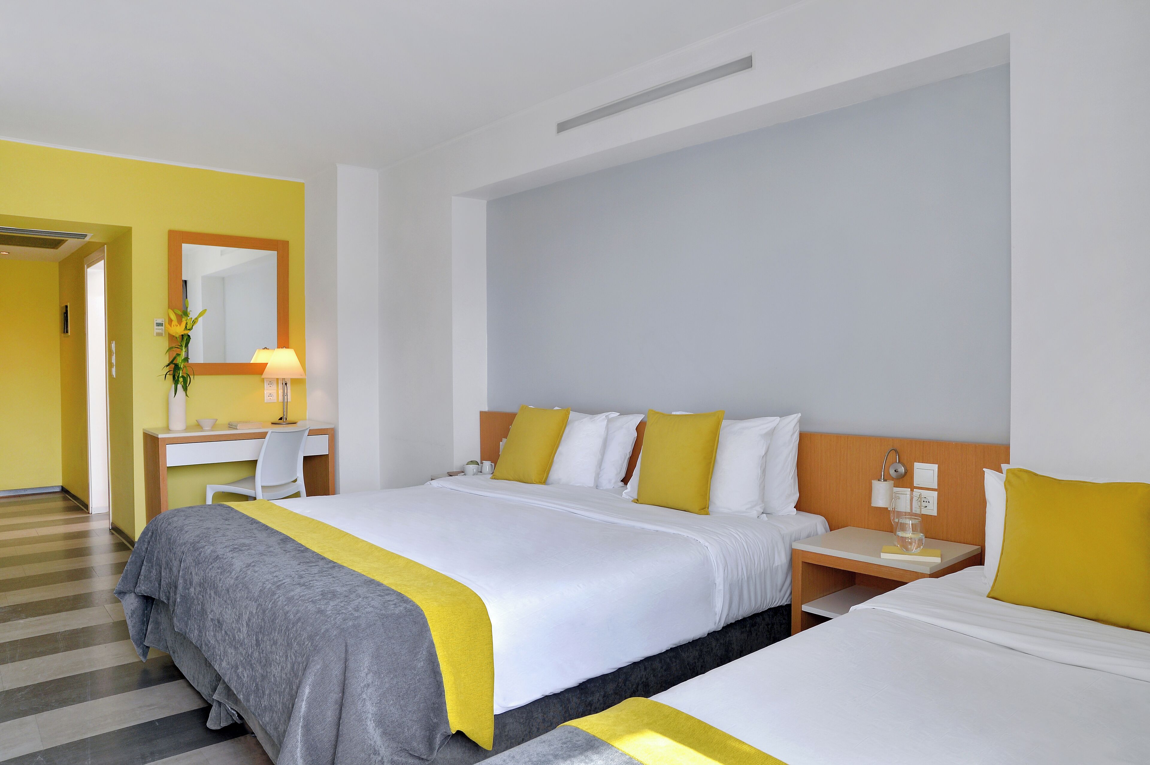A hotel room with a bed, bedside table, and a desk with a chair.
