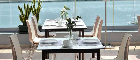 Comedor con una mesa lista para seis personas, con vistas a un cuerpo de agua.