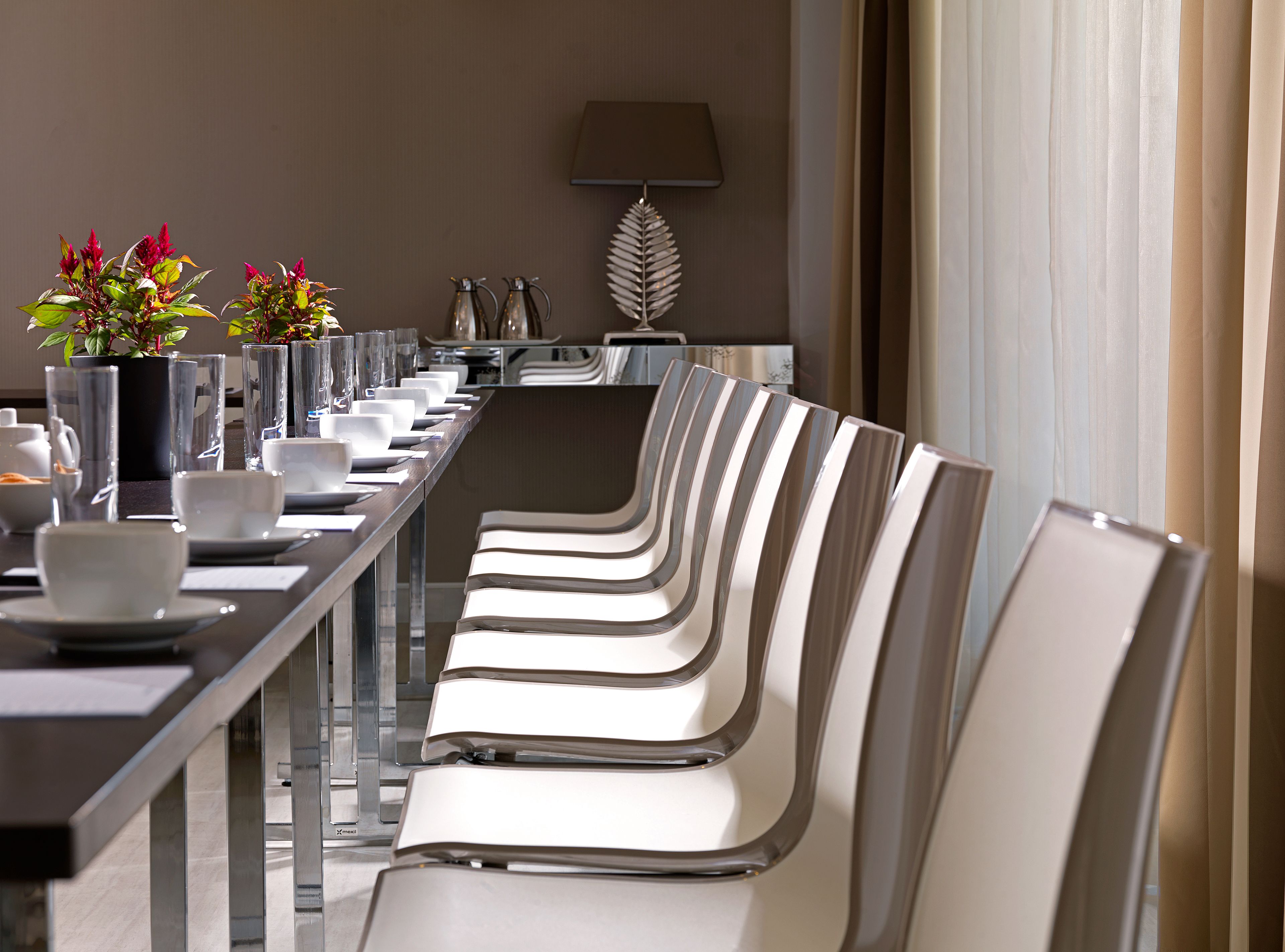 Ein Konferenztisch mit Stühlen, einem Blumentopf und einer Lampe.