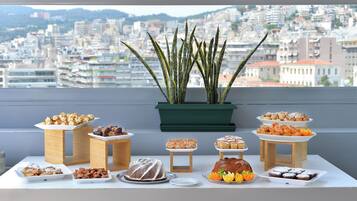 Una mesa de buffet con diversos postres y una planta en maceta al fondo.