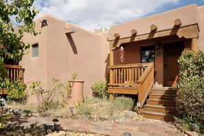 A building with a wooden deck, a door with a window, and a small flag. - Casa Cuma Bed & Breakfast (Santa Fe)