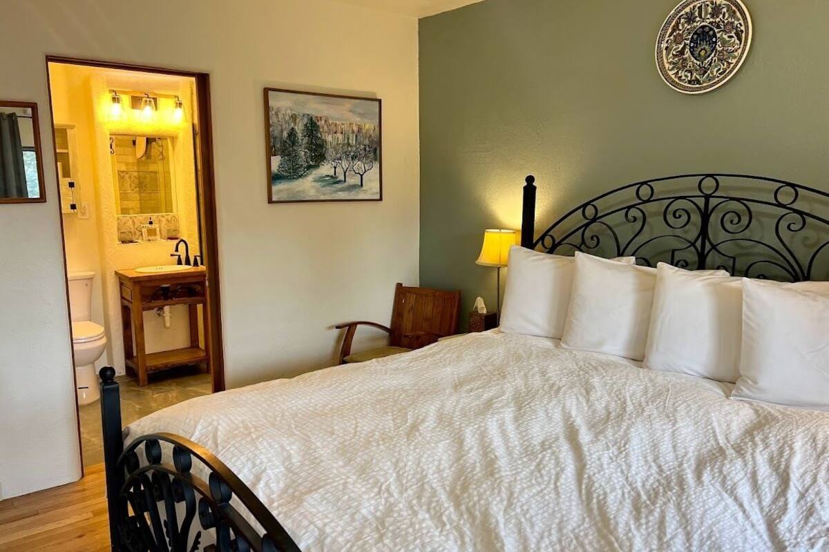 A bedroom with a bed, a bedside lamp, a painting, and a decorative plate on the wall.